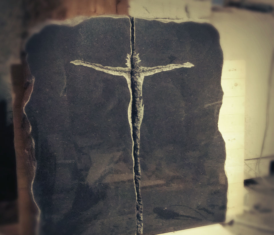 Tablica nagrobna z Jezusem wykutym w szczelinie granitowego kamienia.