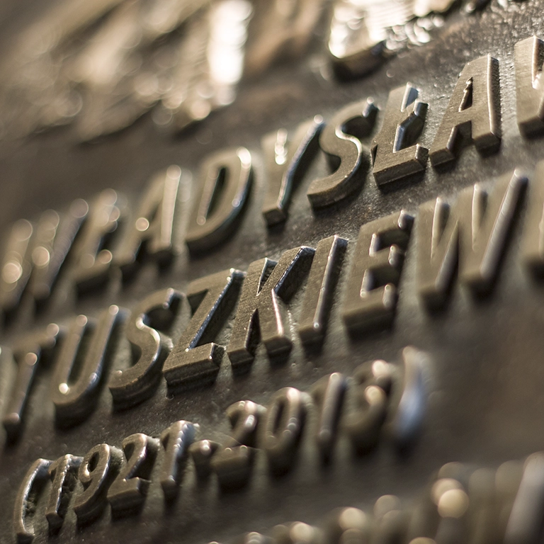 Tablica pamiątkowa - liternictwo Tablica pamiątkowa, na której znalazł się tekst, który jest zaprojektowany według zasad kompozycji.