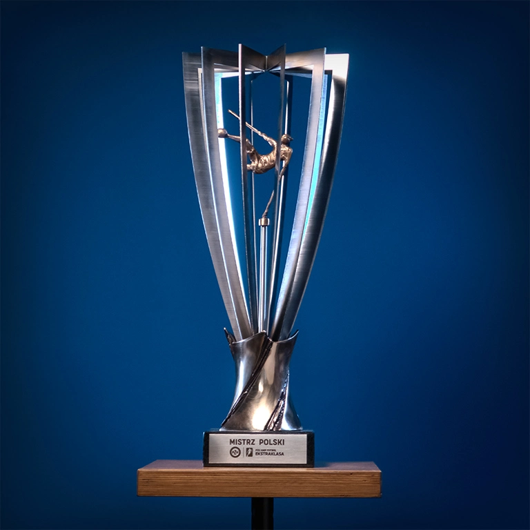 Trofeum Mistrza Polski PZU Ekstraklasa o wysokości 60 cm, wykonane z brązu, stali nierdzewnej i granitu, z rzeźbą Amp futbolowego piłkarza w środku.